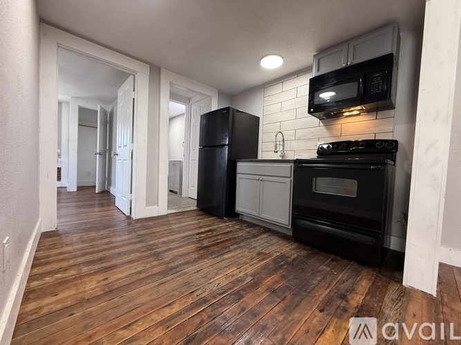 A kitchen with black appliances and wooden floors.