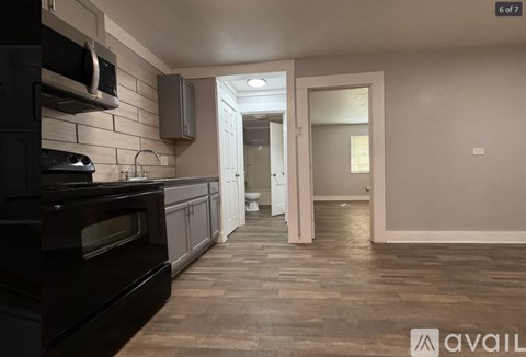 A kitchen with black appliances and wooden floors.