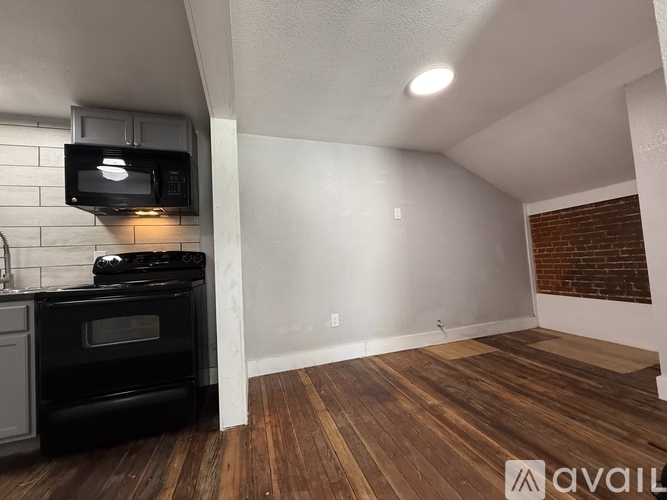 A long hallway with wood flooring and a black cabinet.