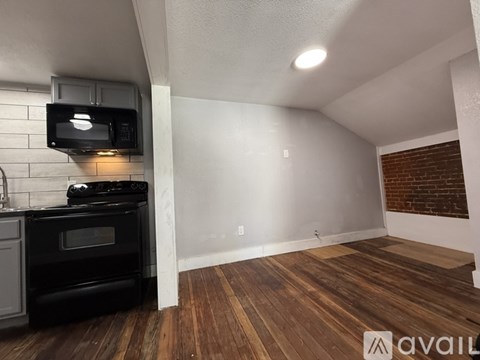 A long hallway with wood flooring and a black cabinet.