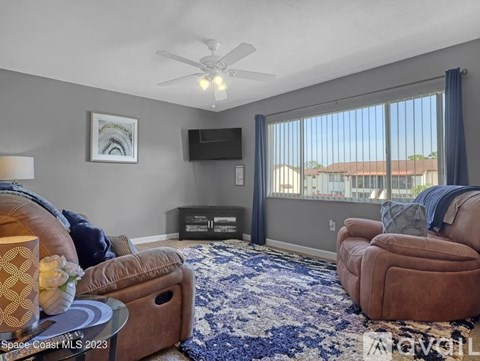 A living room with a brown chair and a blue and white rug.