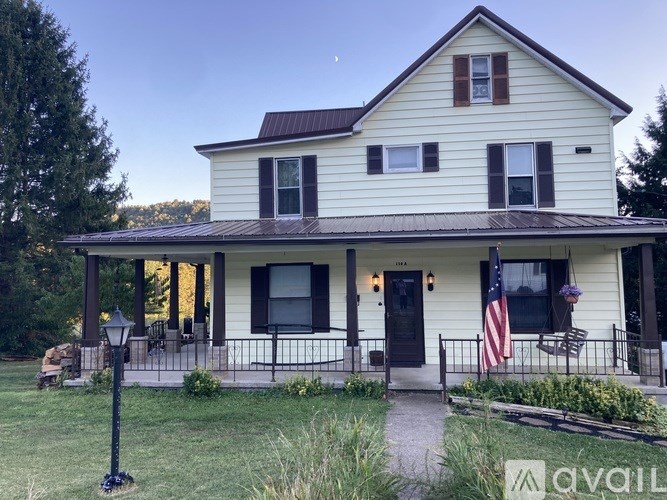 A white house with a red container in front of it.