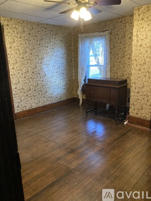 A room with wooden floors and floral wallpaper.