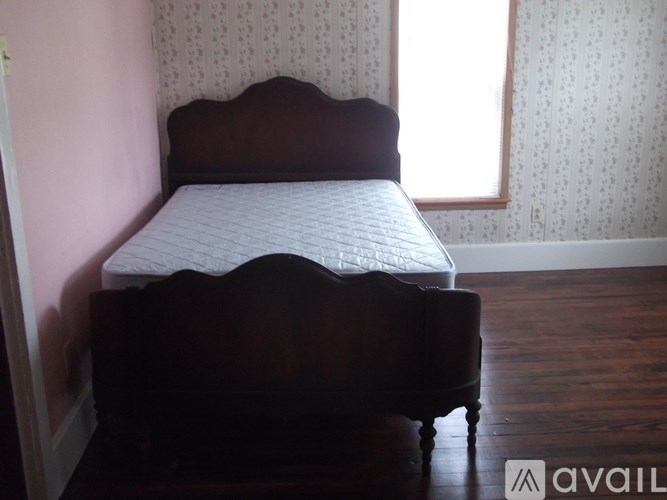A bed with a wooden headboard and footboard sits in a room with a window.