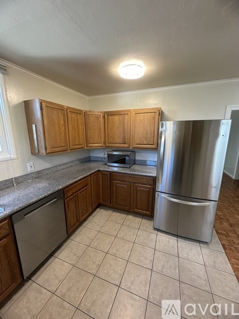 A kitchen with wooden cabinets and a stainless steel refrigerator.