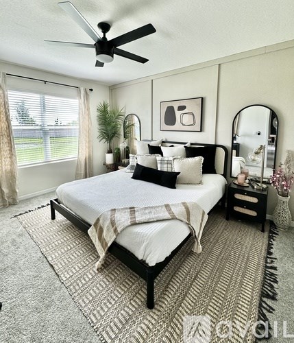 A bedroom with a bed, a mirror, and a ceiling fan.