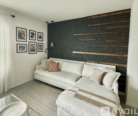 A living room with a white couch and a wooden accent wall.