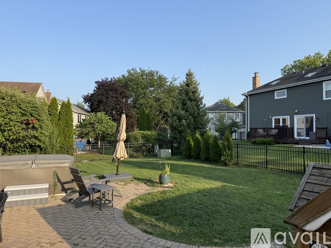 A backyard with a patio, lawn, and a pool.