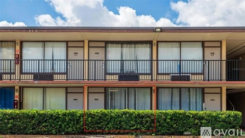 A building with balconies and a hedge in front.