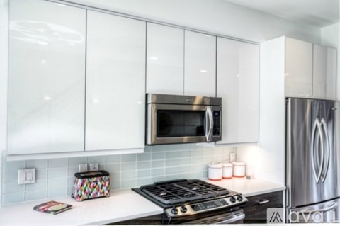 A modern kitchen with white cabinets and a stainless steel refrigerator.