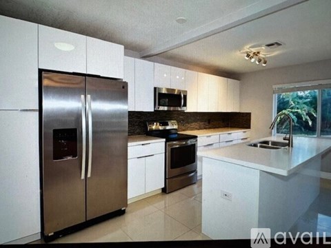 A modern kitchen with a stainless steel refrigerator and white cabinets.