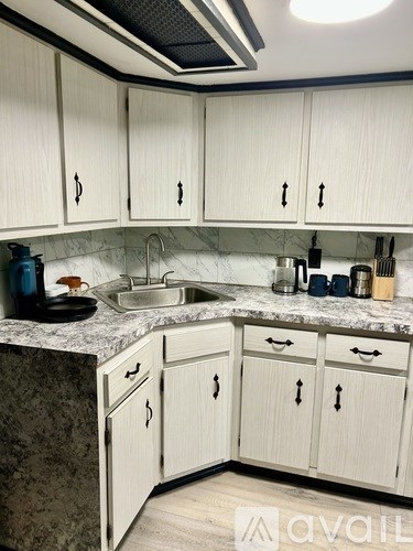 A kitchen with white cabinets and a marble countertop.