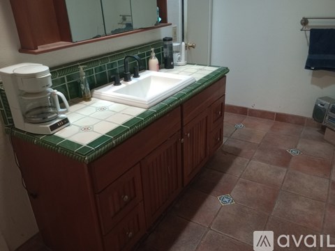 A kitchen with brown cabinets and a green tile backsplash.