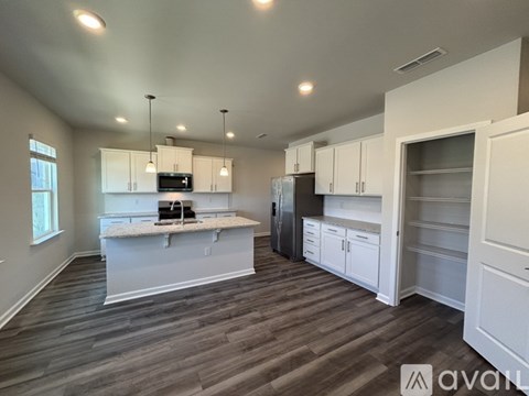 A kitchen with white cabinets and a wooden floor.