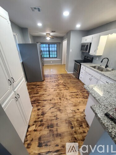 A kitchen with wooden floors and white cabinets.