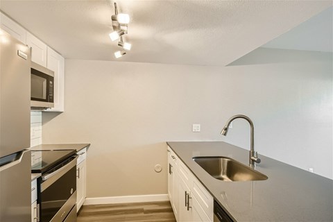 A kitchen with a stainless steel sink and a refrigerator.