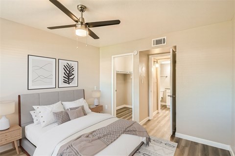 A bedroom with a bed, a ceiling fan, and a nightstand.
