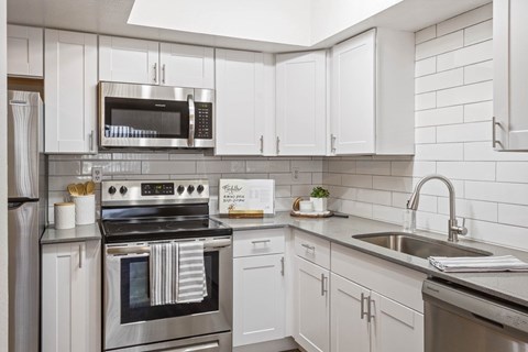A modern kitchen with white cabinets and stainless steel appliances.