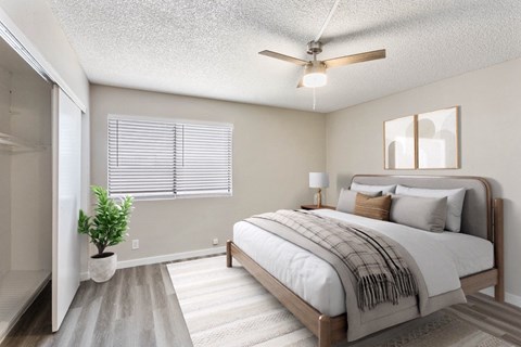 A bedroom with a bed, a plant, and a ceiling fan.