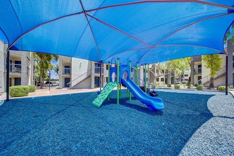 A playground with a blue canopy and a green slide.