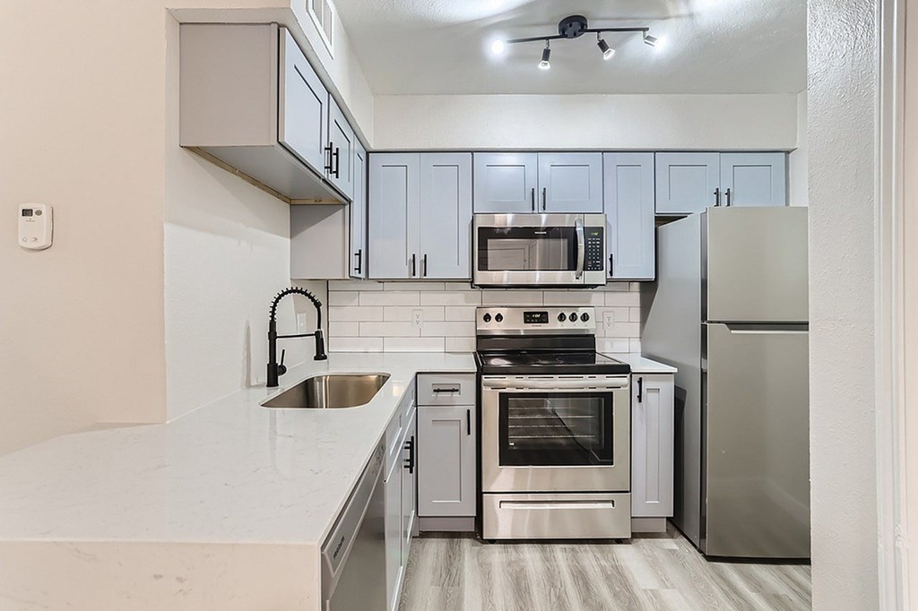 A modern kitchen with stainless steel appliances and white cabinetry.