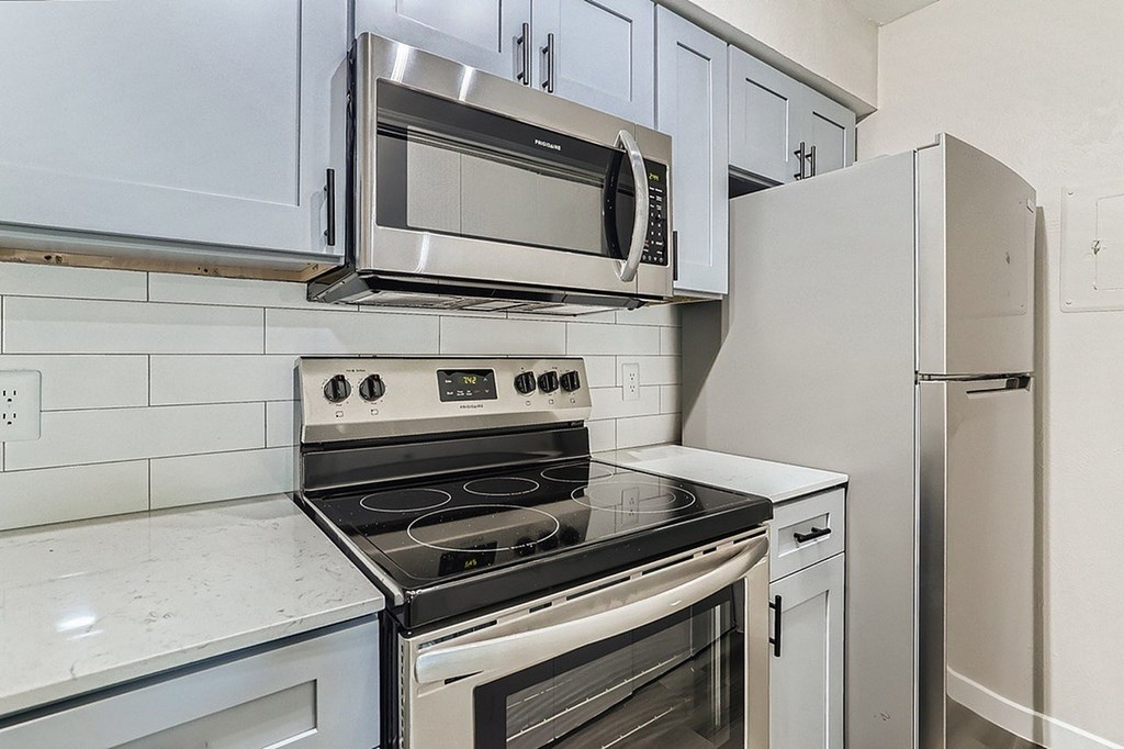 A kitchen with a stove, microwave, and refrigerator.