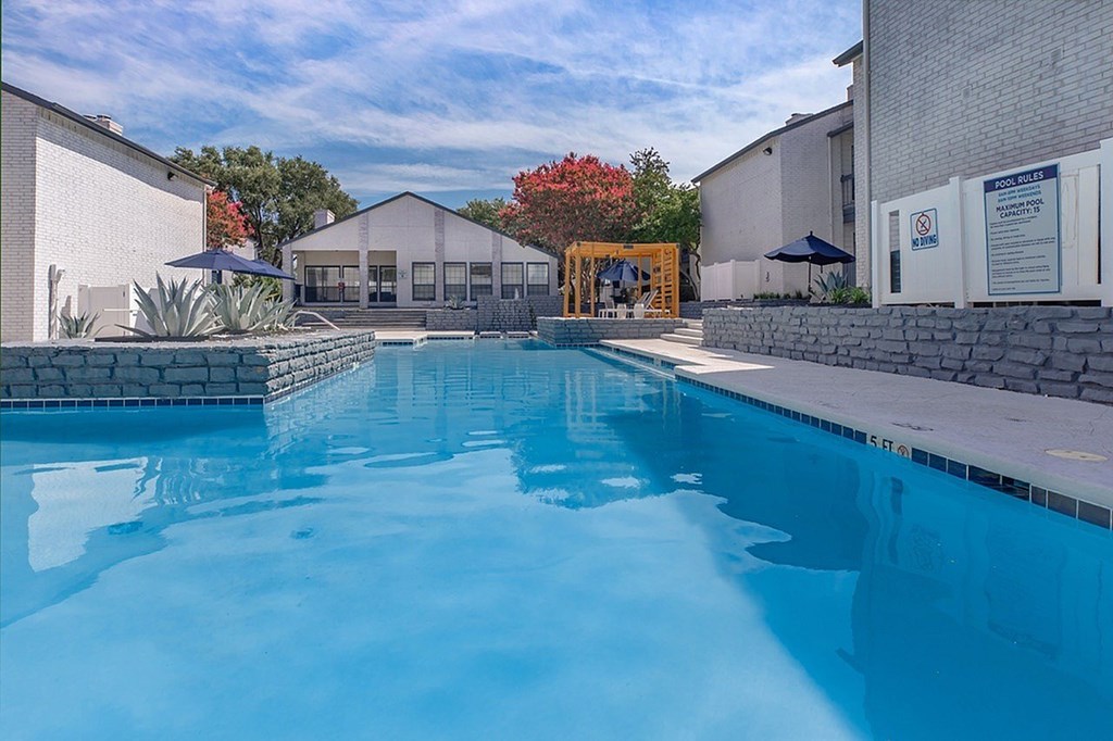 A large swimming pool in front of a building with a yellow gate.