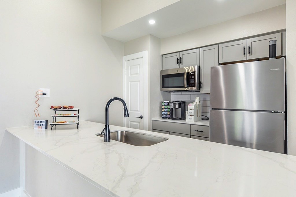 A modern kitchen with a stainless steel refrigerator and a white marble countertop.