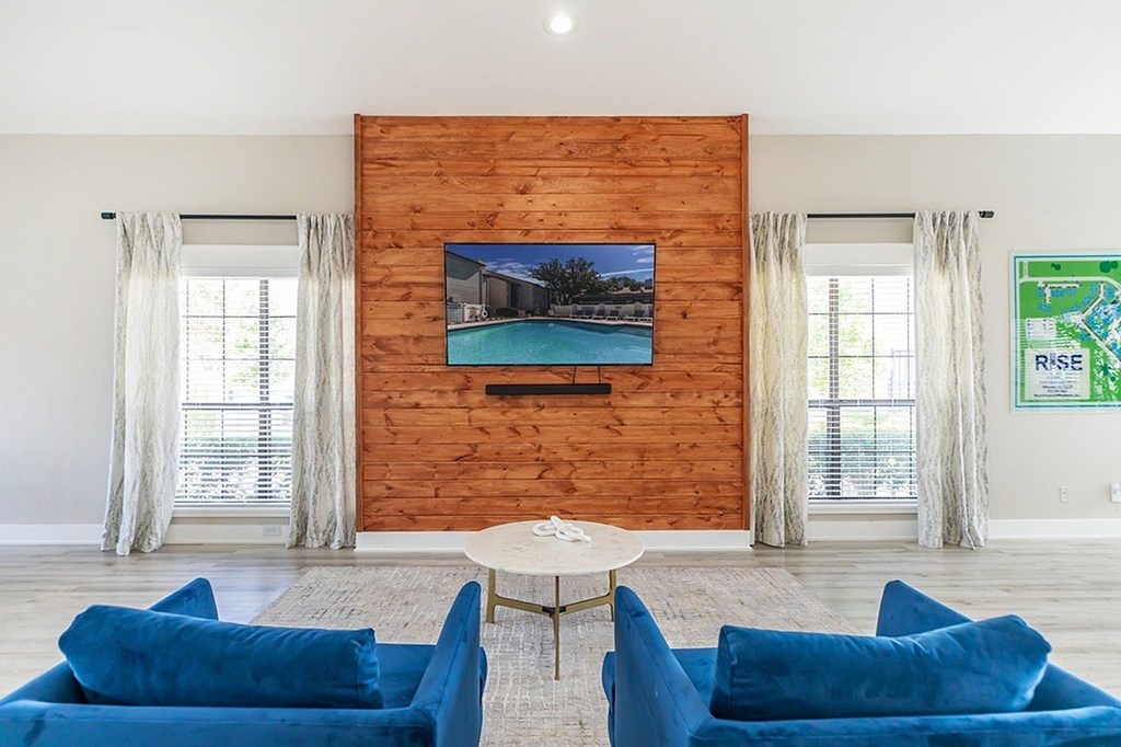 A living room with blue couches and a wooden wall.