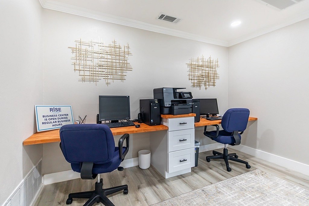 A sign on a desk that says "RISE" is visible in the image.