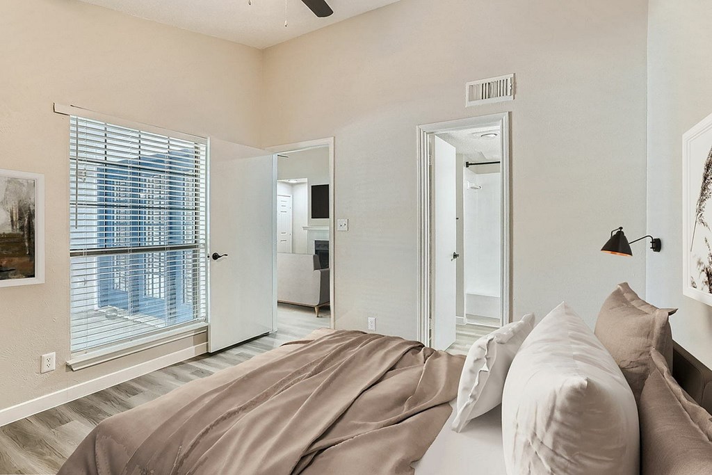 A bedroom with a large bed and a window with blinds.
