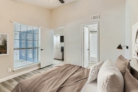 A bedroom with a large bed and a window with blinds.
