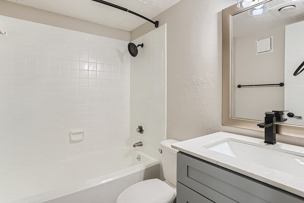 A white bathroom with a toilet, sink, and shower.