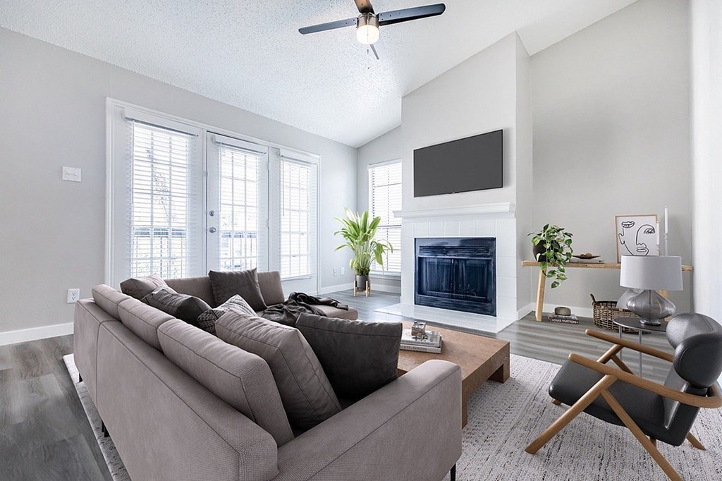 A living room with a grey couch and a fireplace.