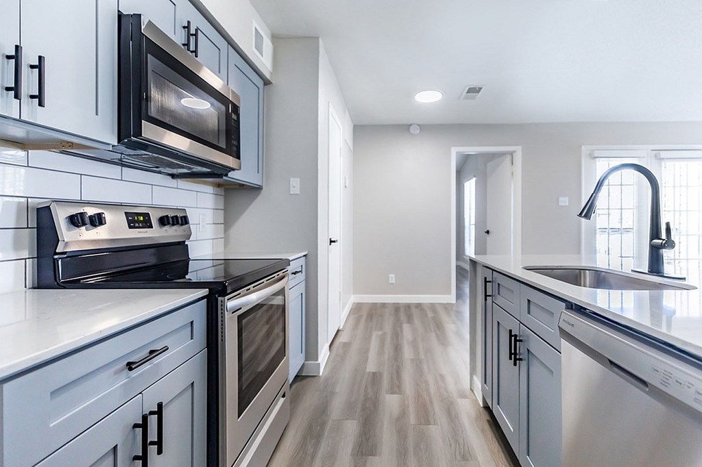 A modern kitchen with stainless steel appliances and wooden floors.