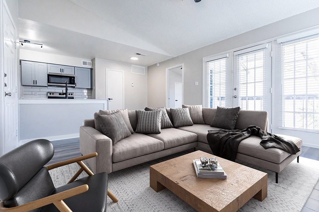 A modern living room with a grey sofa, a wooden coffee table, and a black chair.