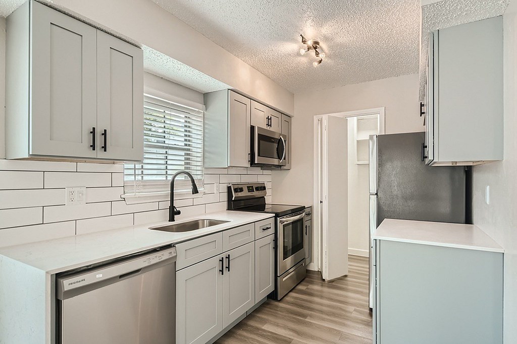 A kitchen with white cabinets and appliances.