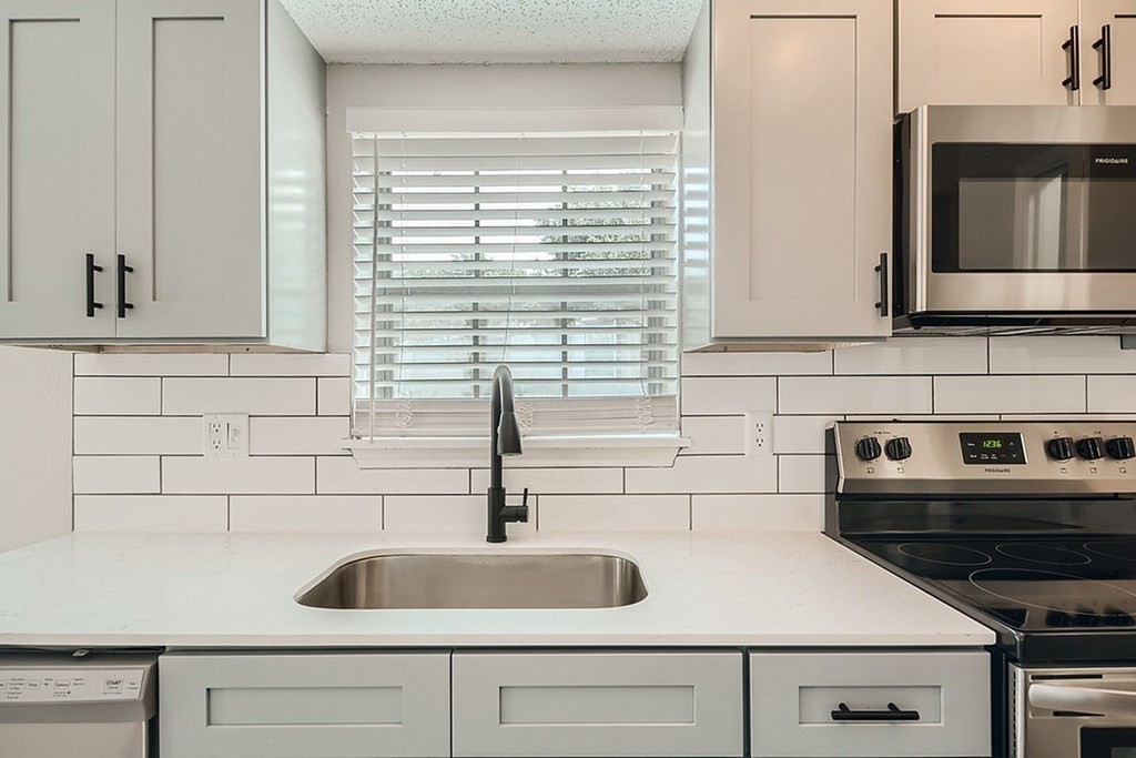 A modern kitchen with a stainless steel microwave above the stove.