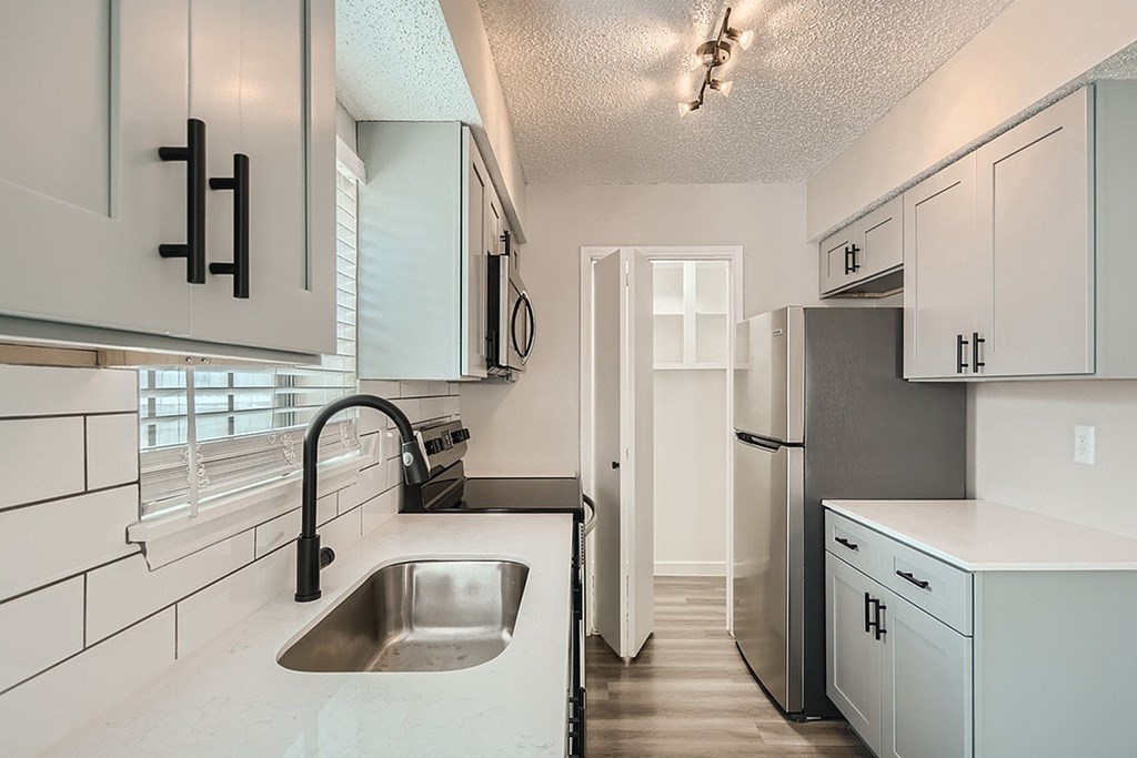A kitchen with white cabinets and a stainless steel sink.