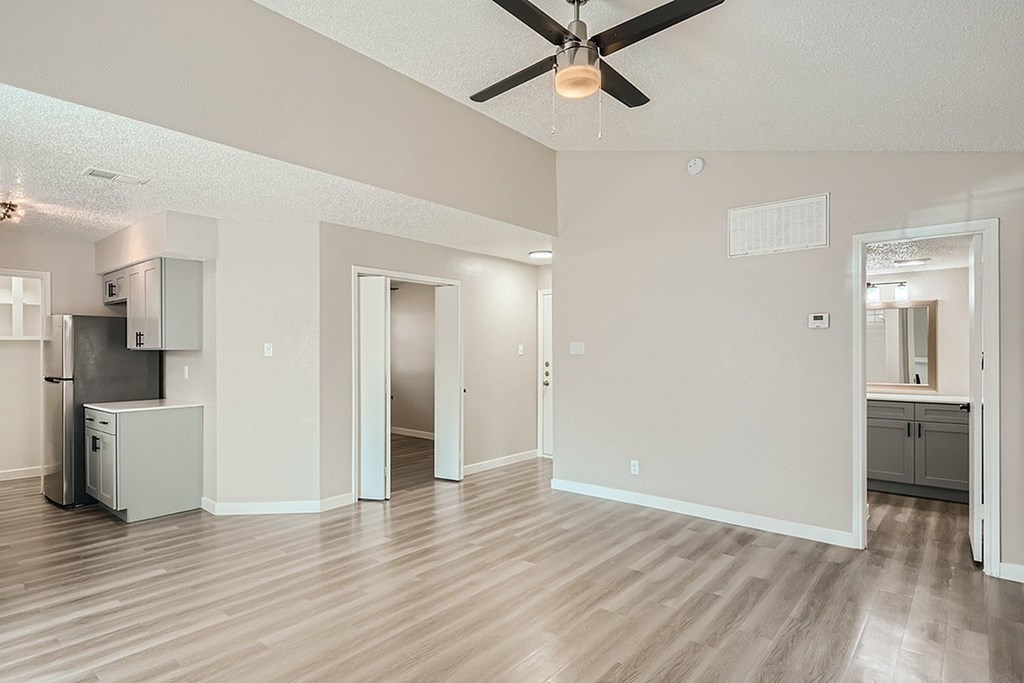 A spacious room with a ceiling fan and wooden flooring.