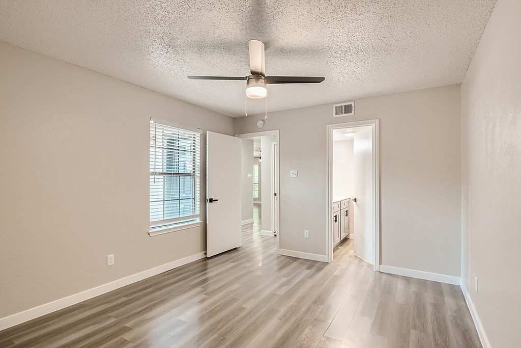 A room with a ceiling fan and wooden flooring.
