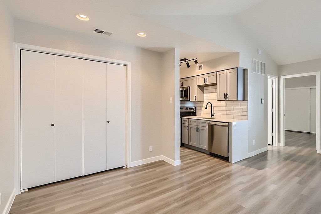 A kitchen with white cabinets and a wooden floor.