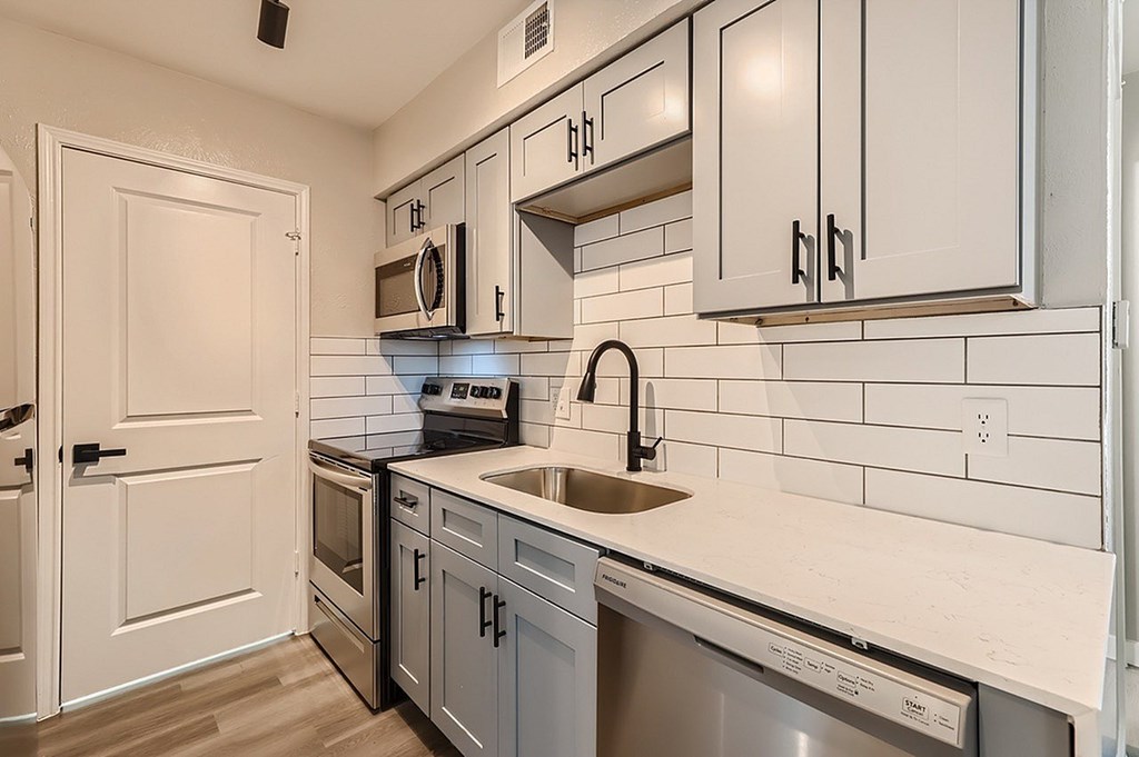 A kitchen with white cabinets and a stainless steel dishwasher.