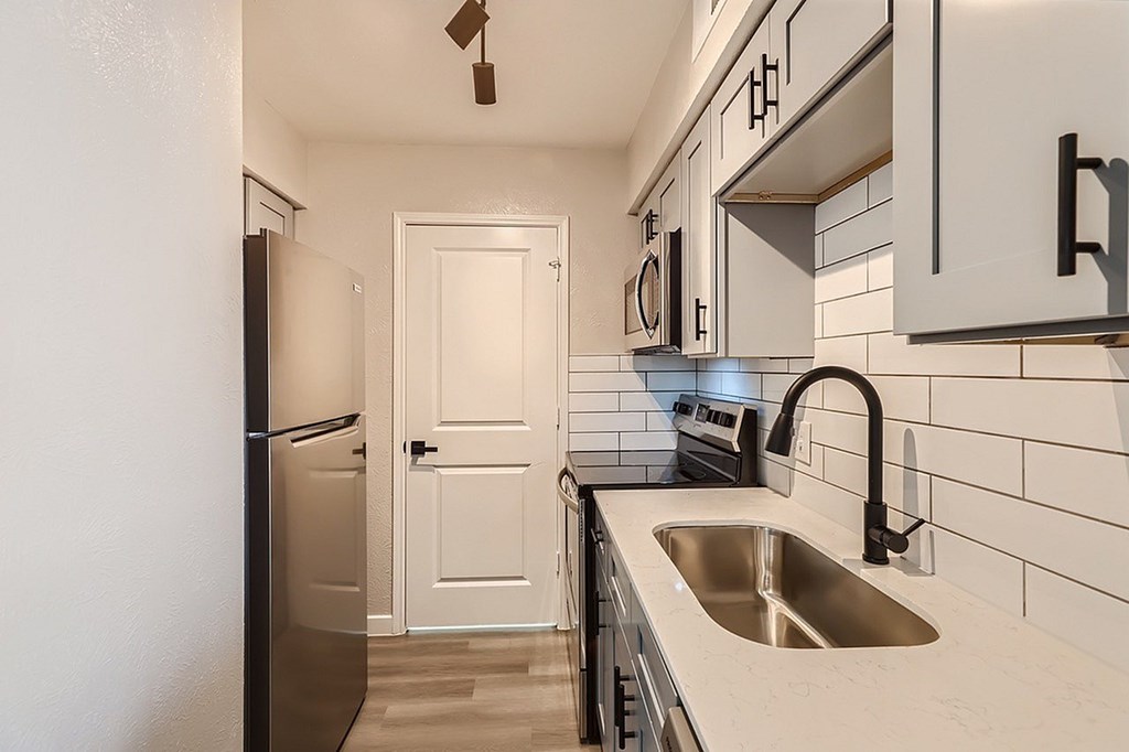 A kitchen with a white door and a black fridge.