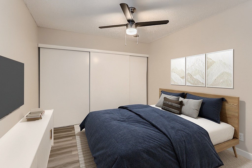 A bedroom with a bed, a ceiling fan, and a wall hanging.