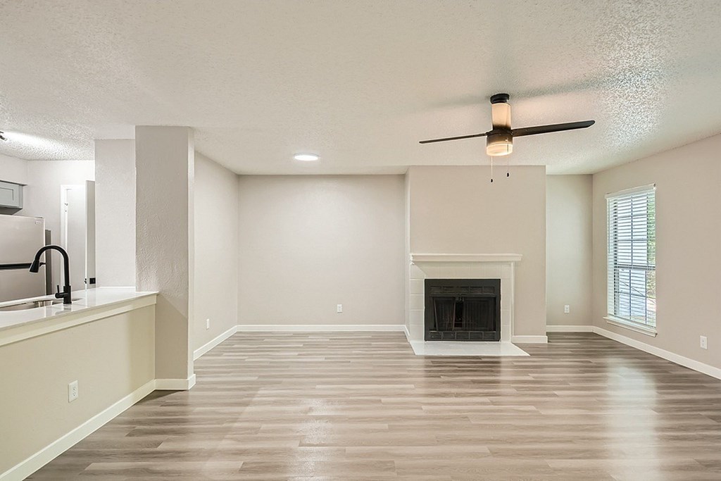 A spacious living room with a fireplace and a ceiling fan.