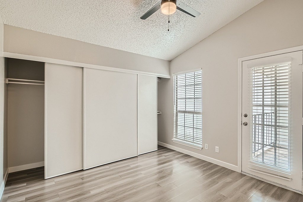 A room with a ceiling fan and sliding doors.