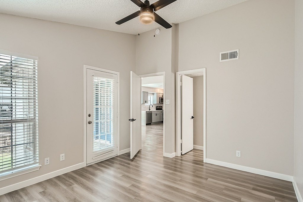 A room with a ceiling fan and wooden flooring.
