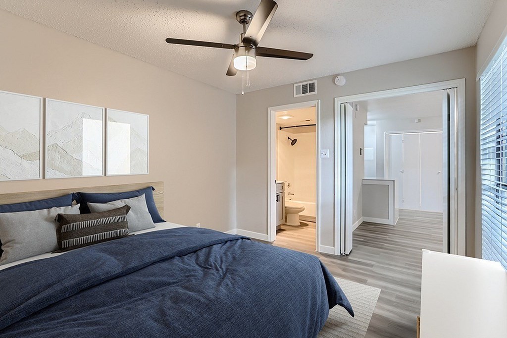 A bedroom with a bed, a ceiling fan, and a view of the mountains through the window.