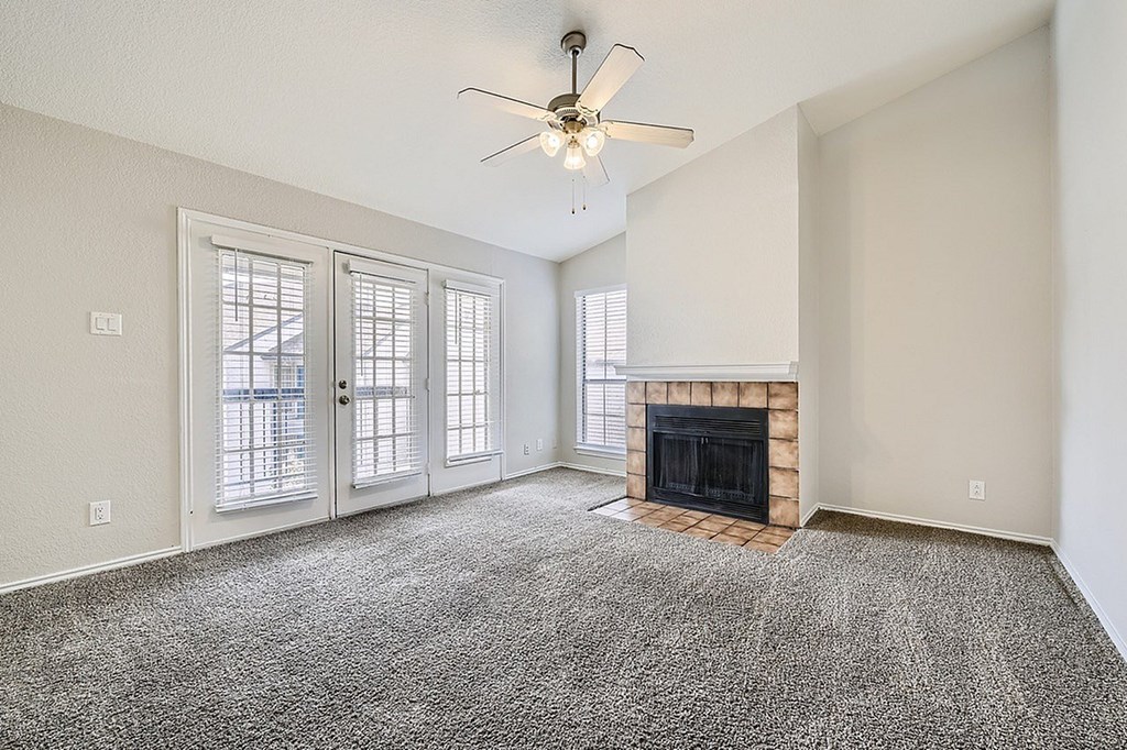 A living room with a fireplace and a ceiling fan.